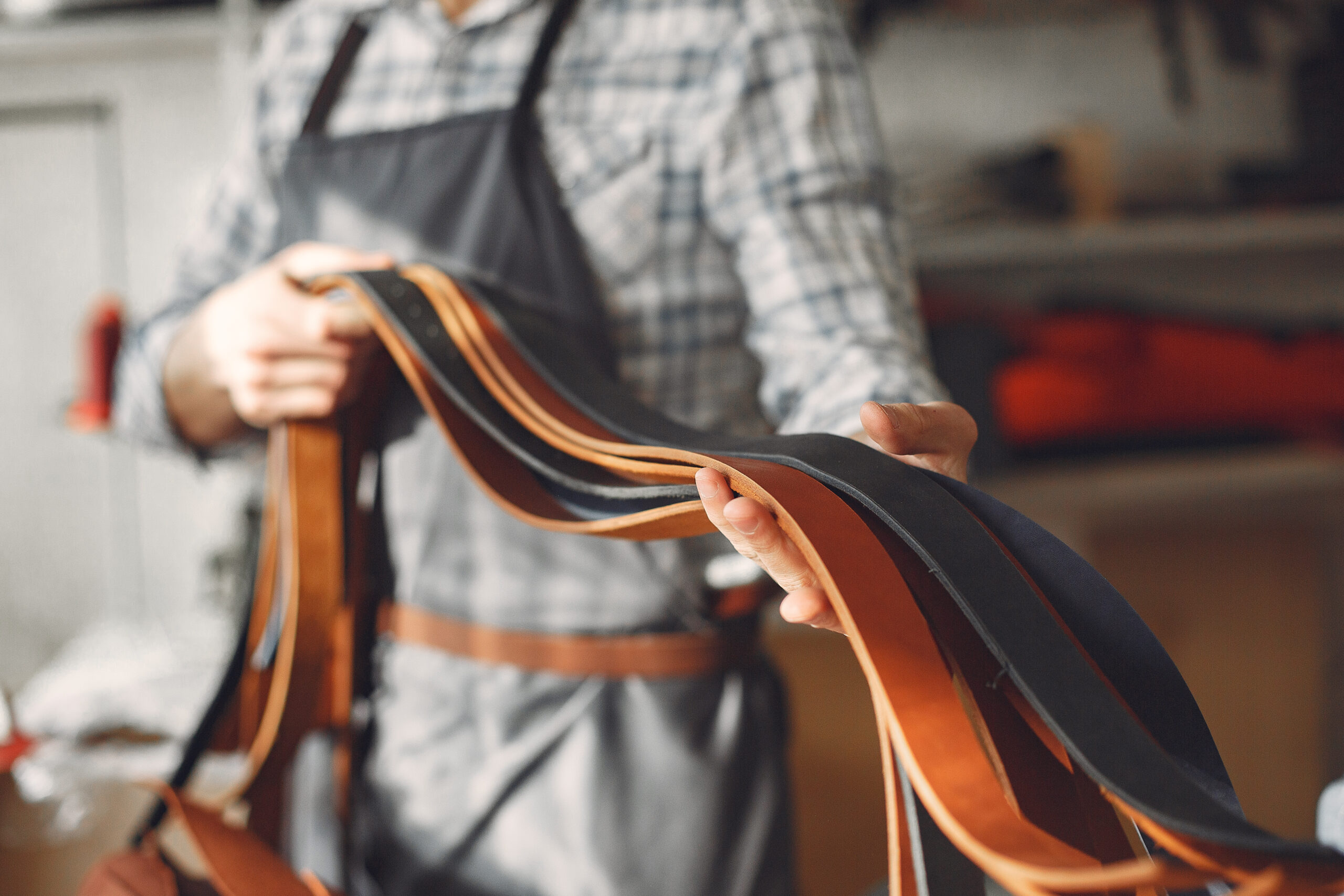 Man working with leather. Professional makes a belts.